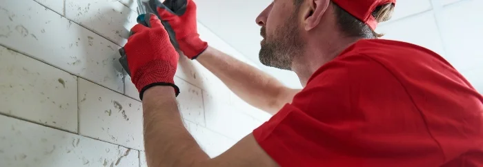 Person montiert Gerät an Wand.